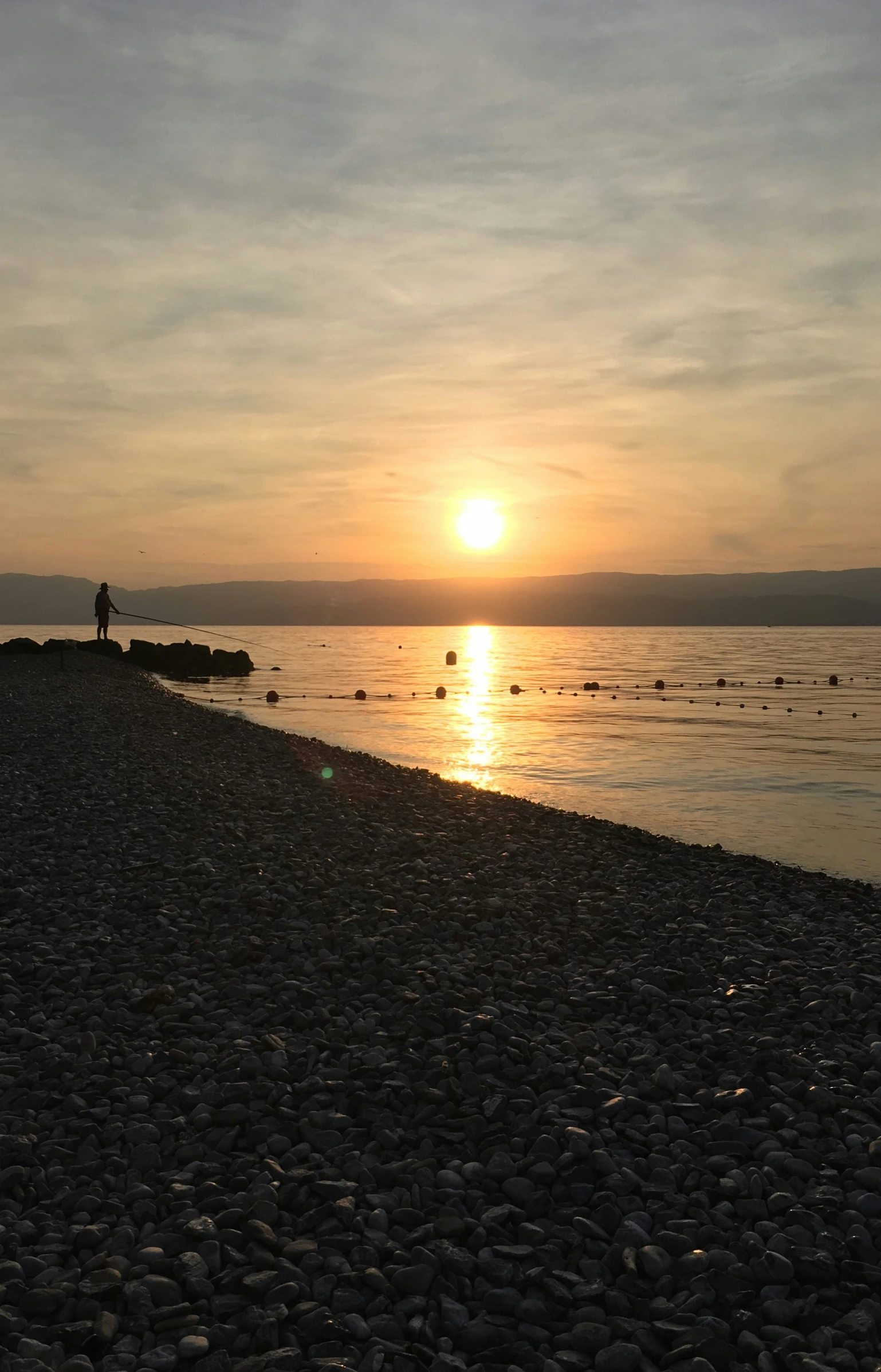 there are people walking on the beach at sunset