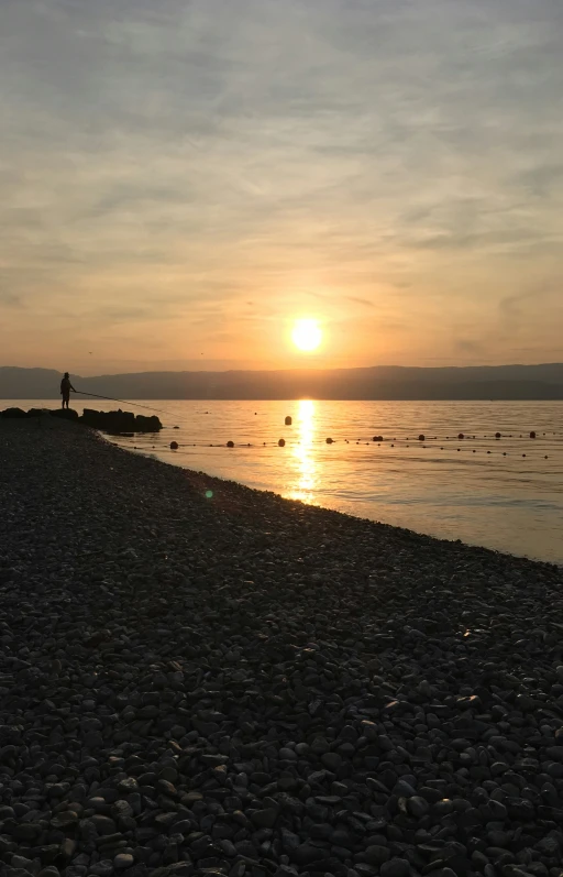 there are people walking on the beach at sunset