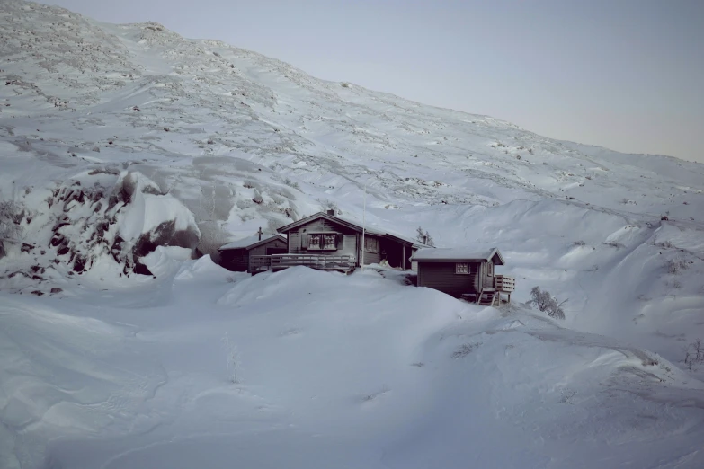 a small house sitting between mountains covered in snow