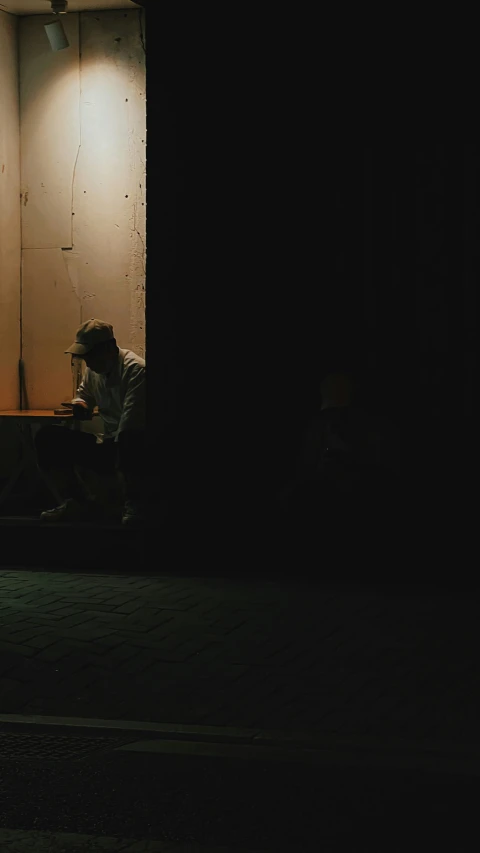 there is a person sitting at night by the wall