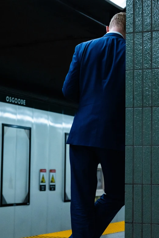 a man in a suit stands by a subway