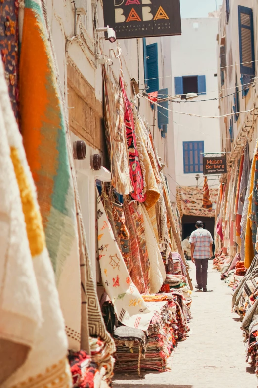 a person walking down an alley way with bags and blankets on it