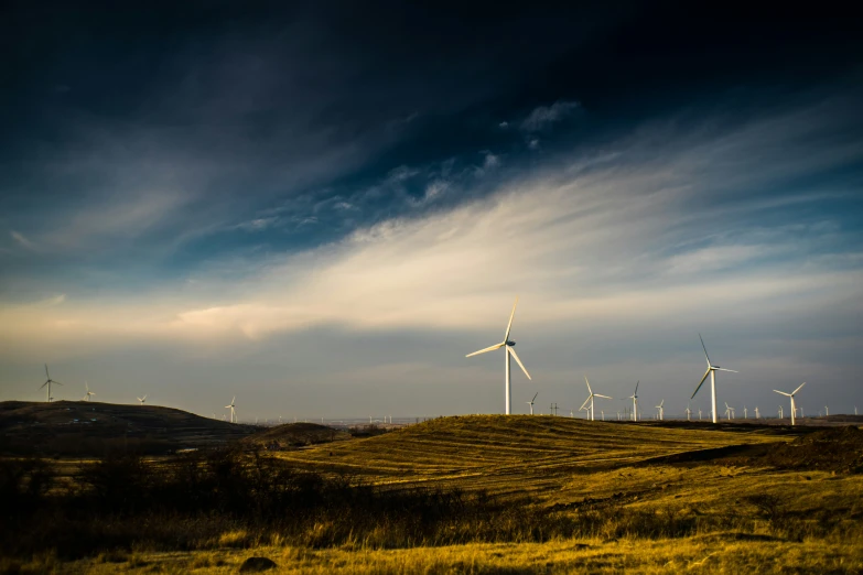 wind turbines are visible under a cloudy blue sky