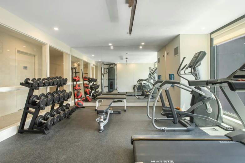 a gym with exercise equipment in rows, on treadmills and machine