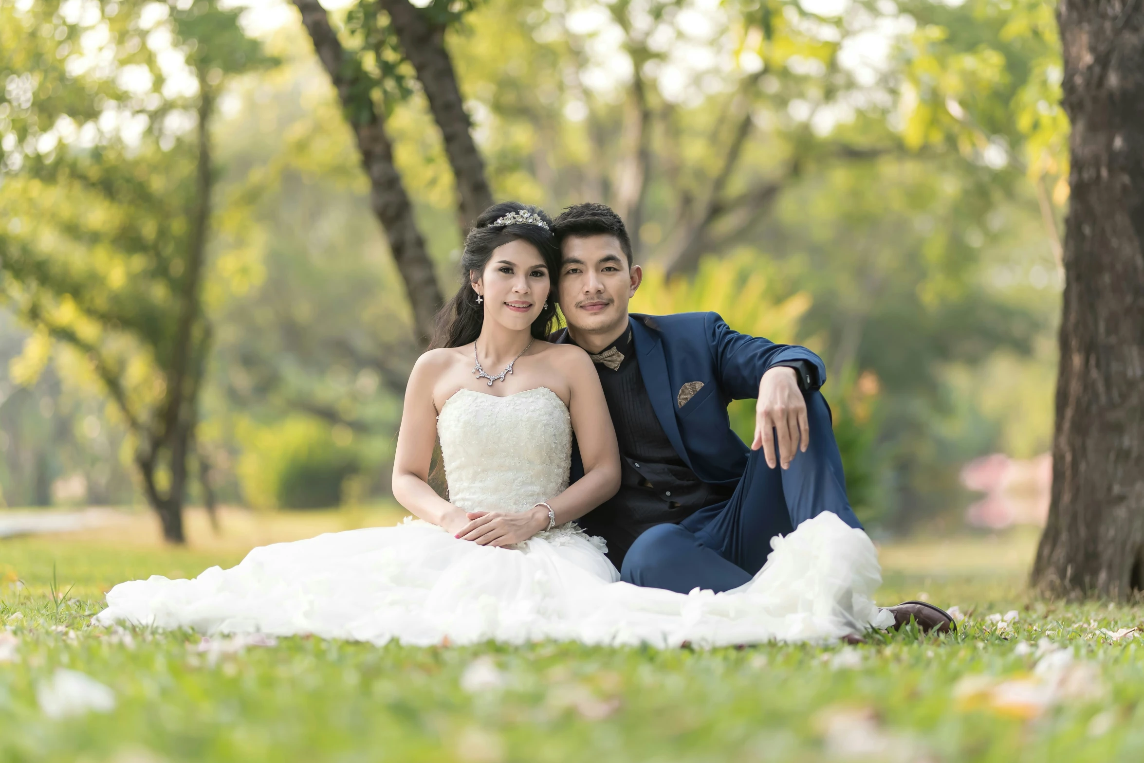 a couple posing for a wedding pograph in front of a tree