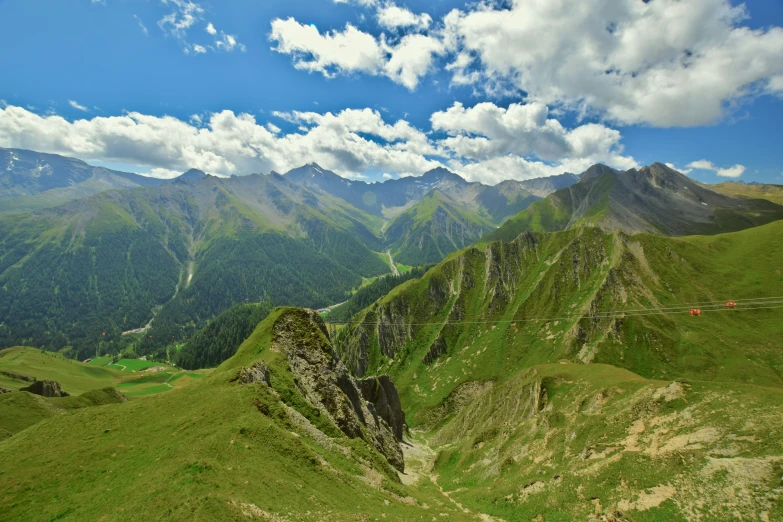 an aerial view of green mountains and clouds