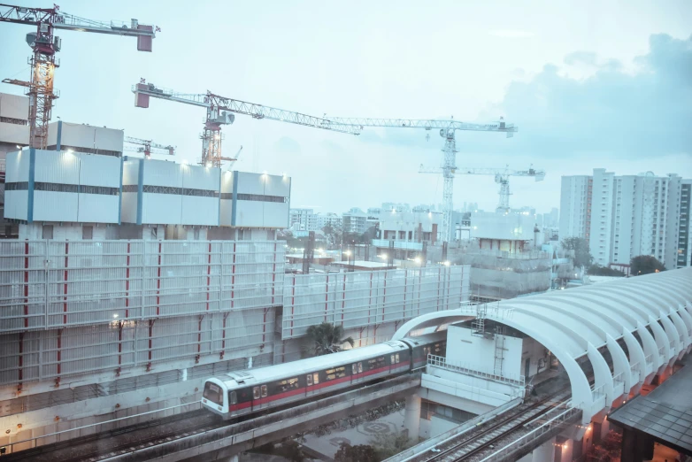 a train is passing through a city as cranes stand over it