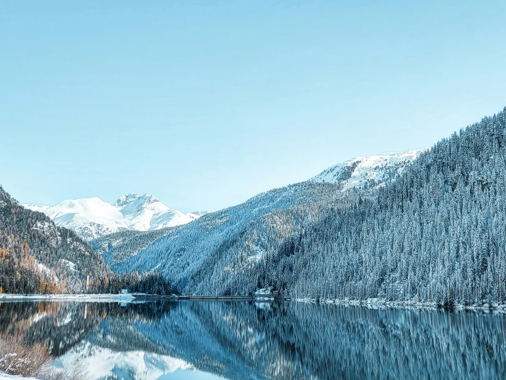 the snow covered mountains near a lake are reflected in the still water