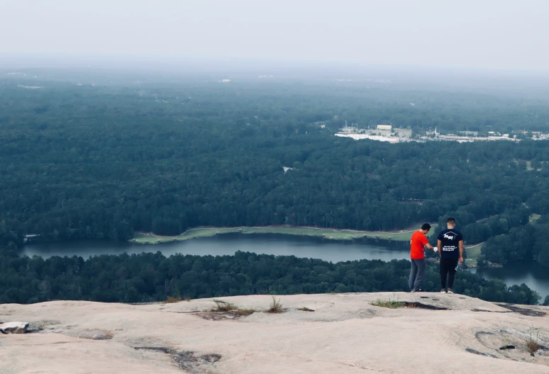 two people on top of a mountain overlooking a body of water