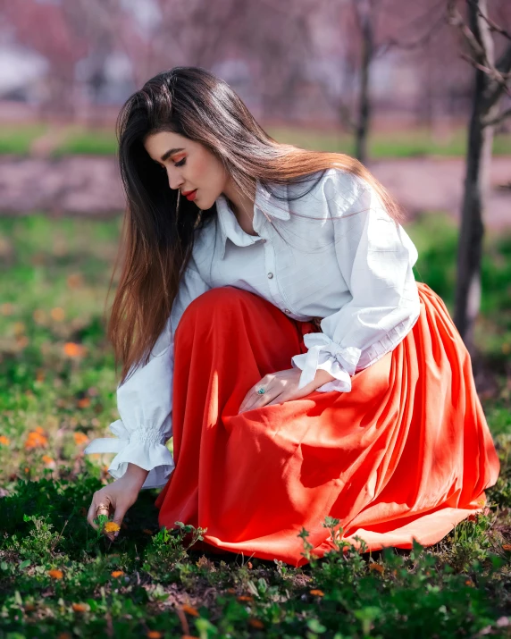 a woman in a white top is sitting on the grass