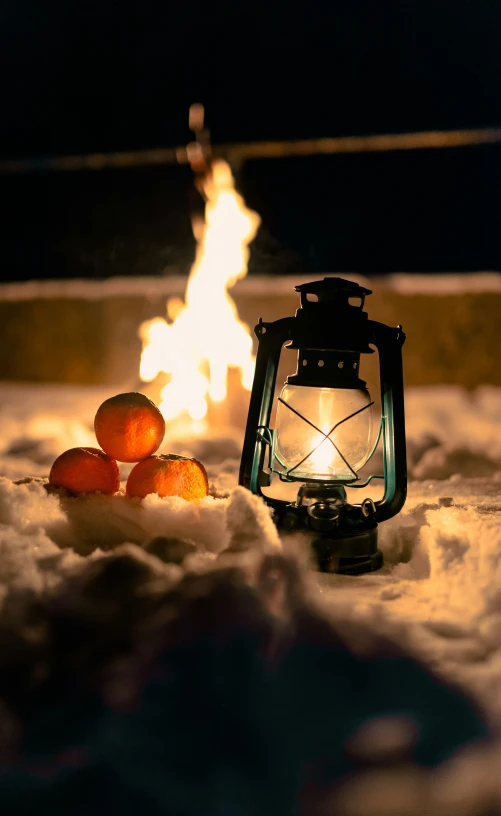 a lantern sitting on top of snow next to a fire