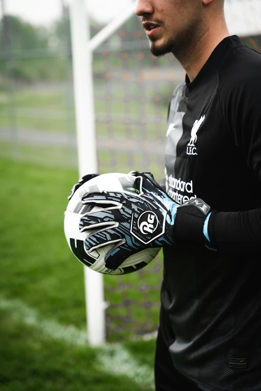 a person wearing a black shirt holding a soccer ball and glove