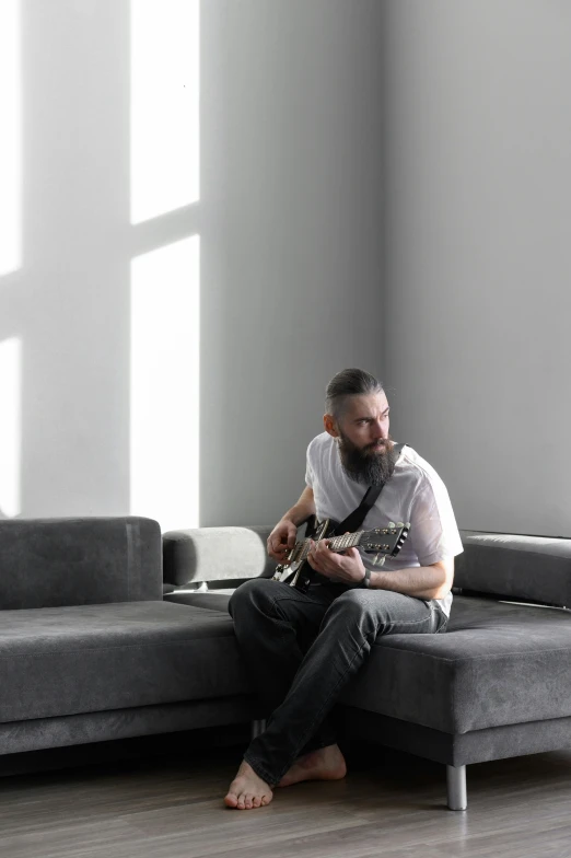 a man playing an acoustic guitar sitting on the couch