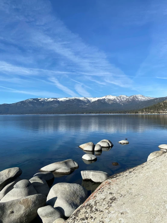 the water is crystal blue and there are stones on the shore