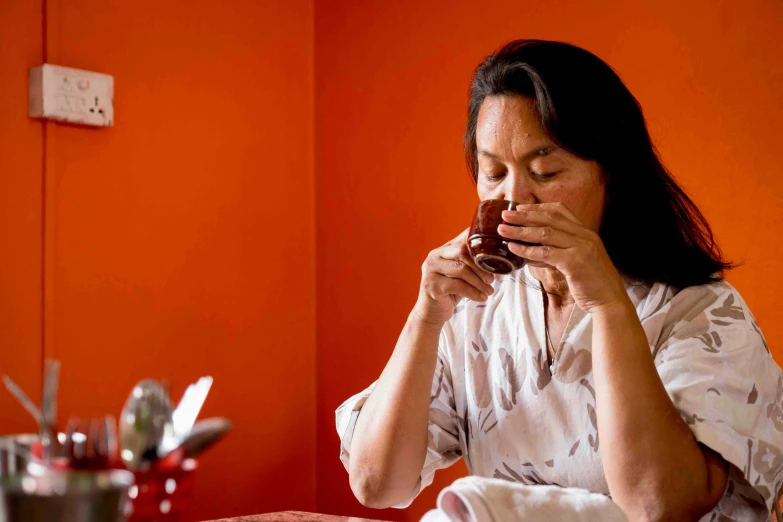 a woman sitting in a chair while drinking a cup of coffee