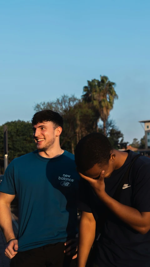 two young men standing next to each other near a stop sign