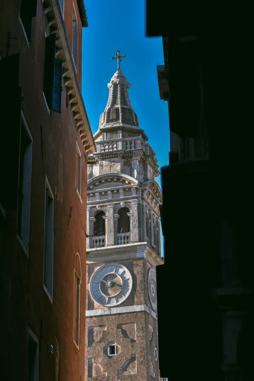 a clock tower behind buildings on a sunny day