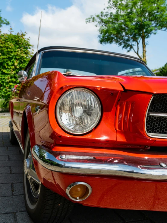 an orange mustang parked on the street in a driveway