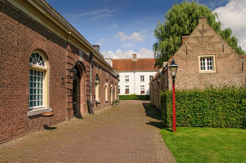 a narrow brick pathway has two windows on either side of the house