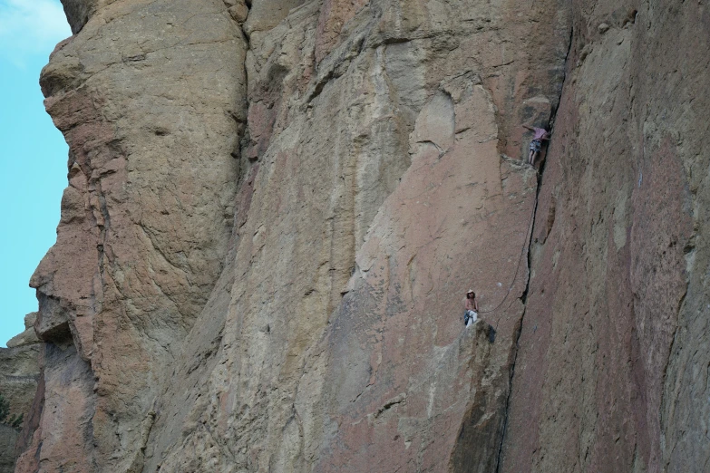 two climbers climbing on steep rock face each other