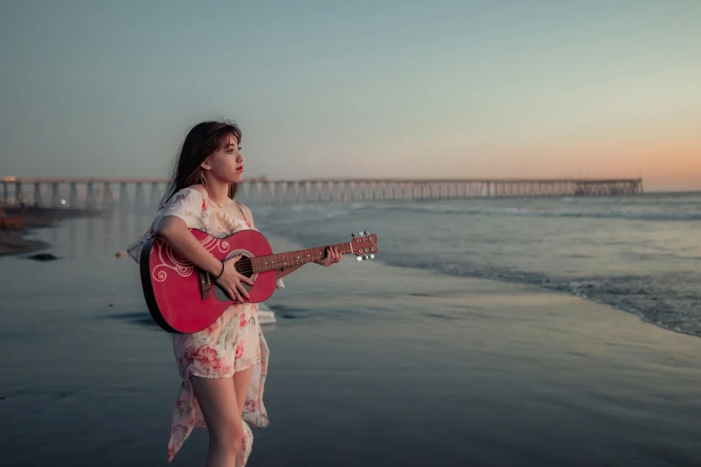 a woman plays the guitar at the beach