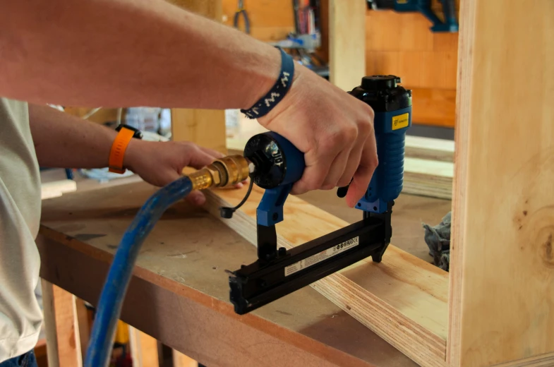 a man holding a small tool that is on top of wood