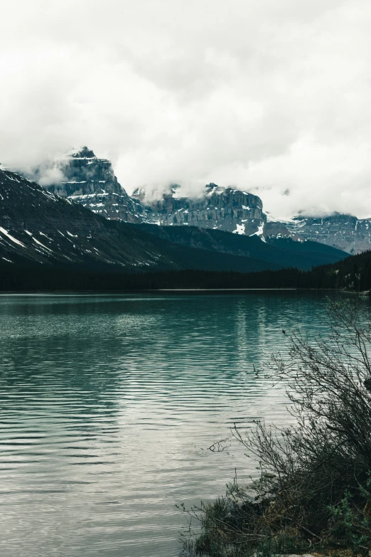 a mountain lake with a few boats in the water and clouds floating in the sky