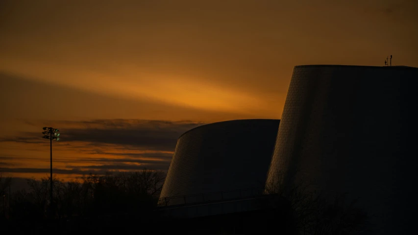 a sunset behind a cooling tower and street lamp