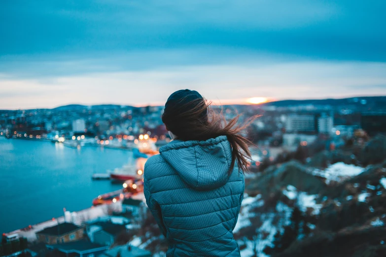 woman overlooking a city and lake during twilight