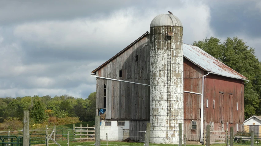 an old barn sits in the middle of a field