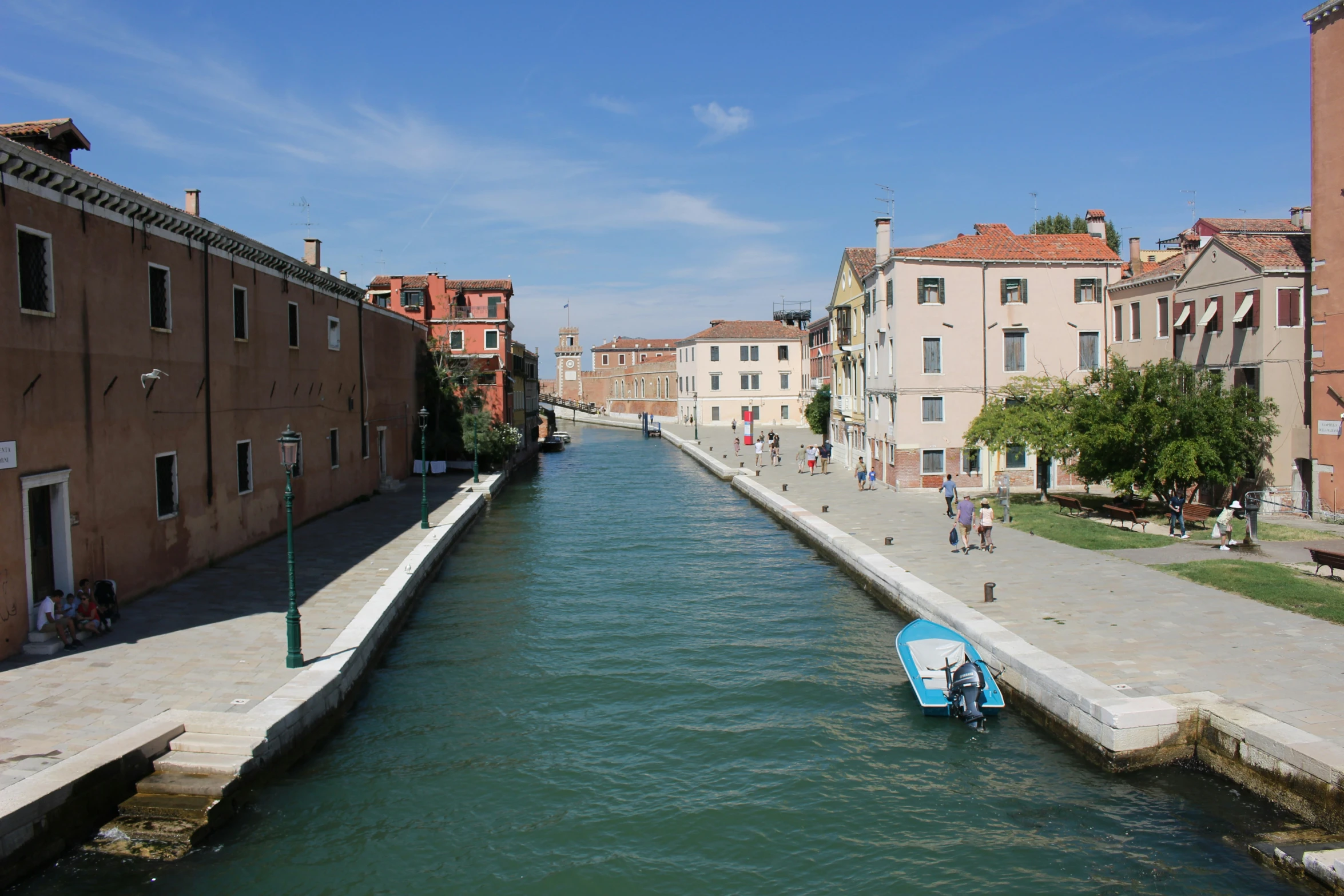 some people are riding boats in a canal next to some buildings