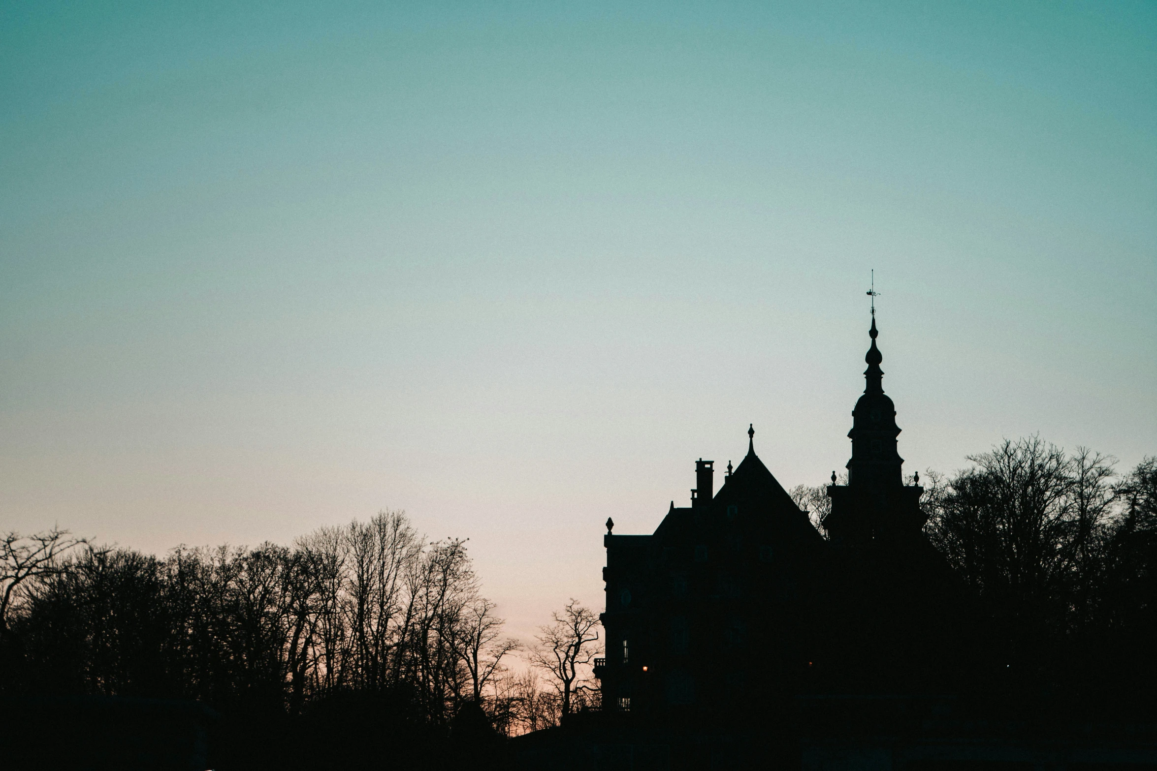 the silhouette of an old building against a blue sky