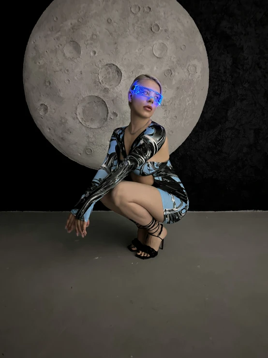 a woman is kneeling down with a large moon behind her