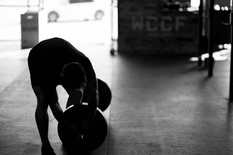 a man stands on his knee while working out with a medicine bag