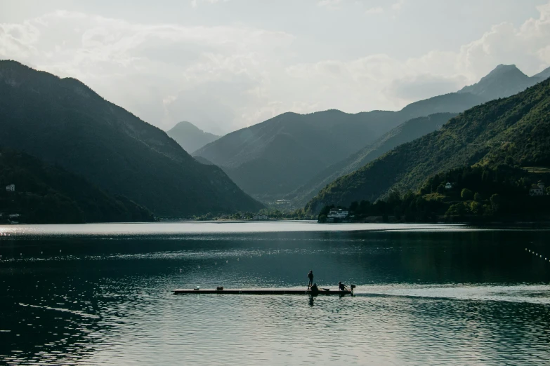 two people on a small boat in a lake near mountains