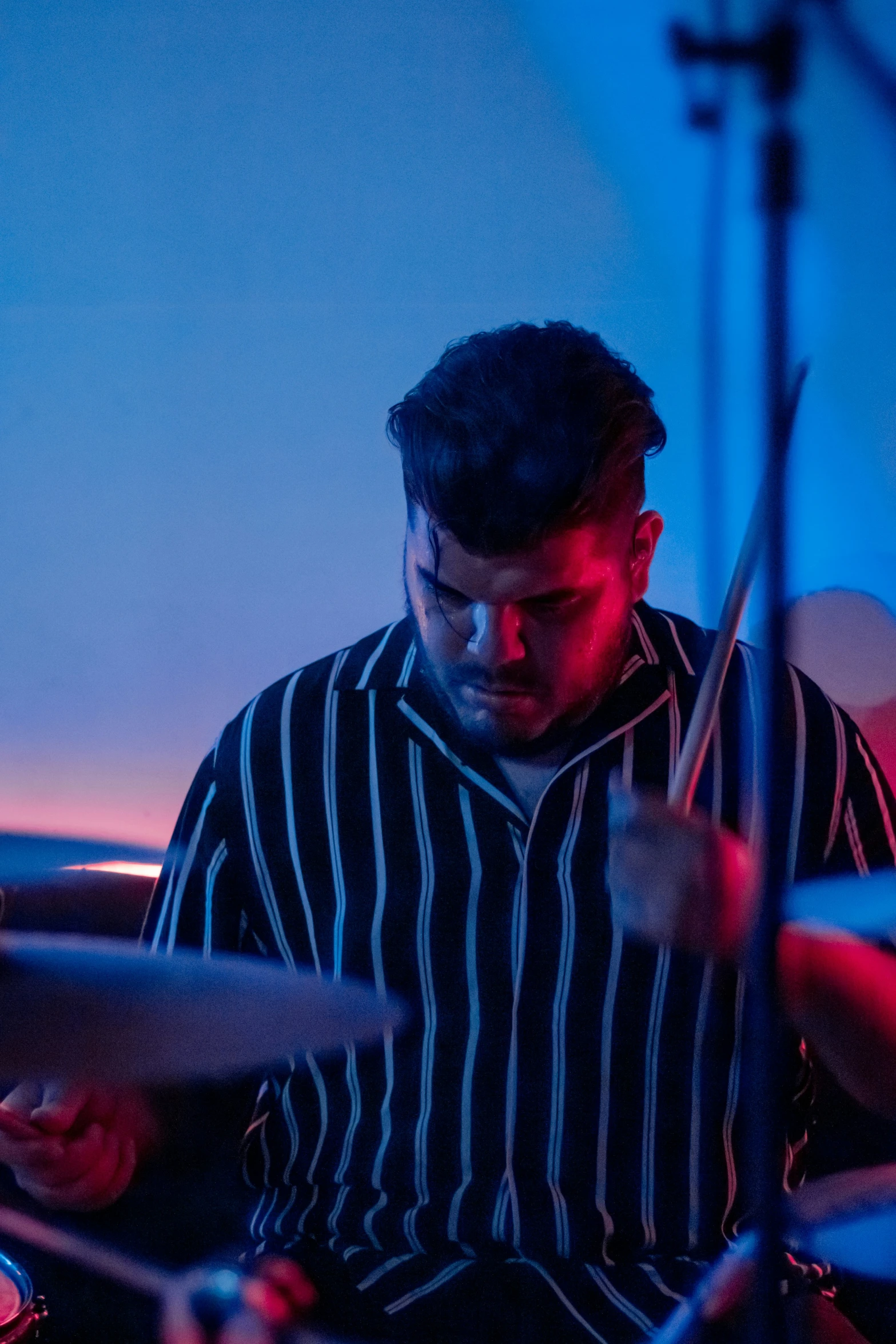 drummer playing drums in a blue lit room