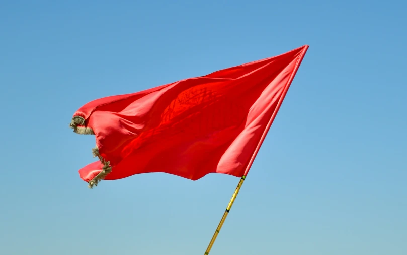 the big red flag flies against a blue sky