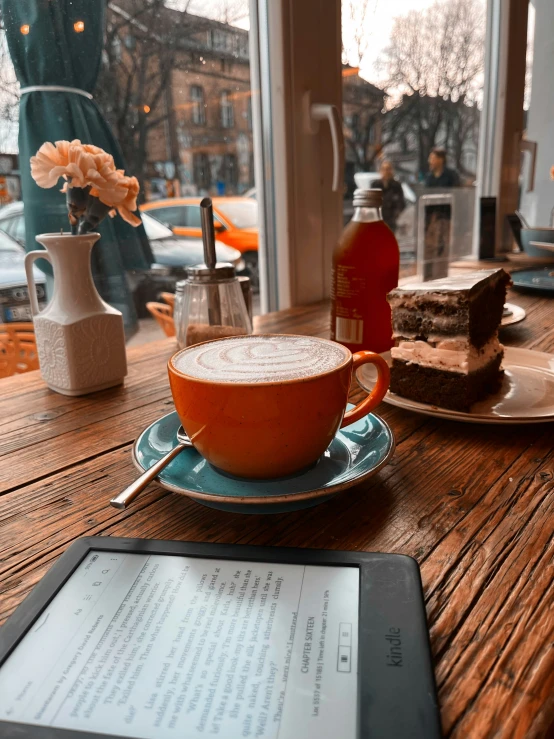 a tablet next to a tea cup on a table