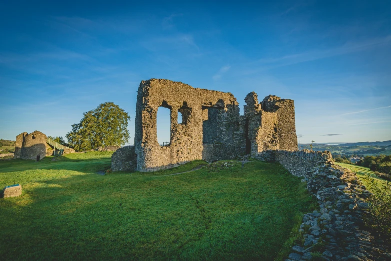 a tall stone castle on top of a green hillside