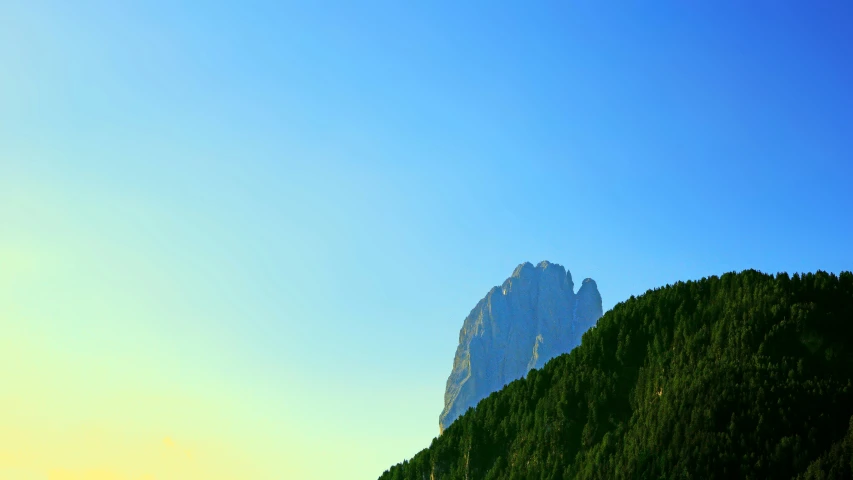 a mountain is shown with green trees in the foreground