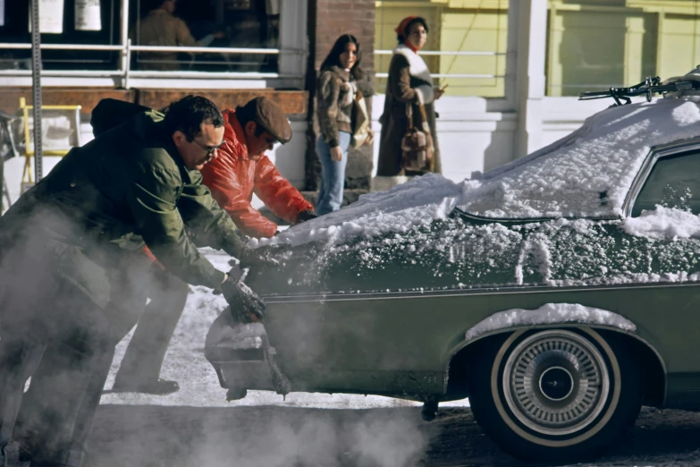 people standing in front of a car in the snow