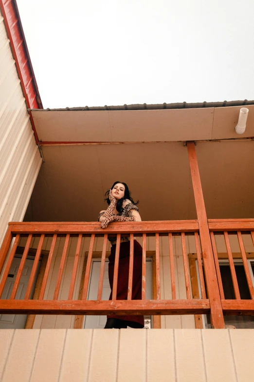 the woman is standing on her balcony talking on her cell phone