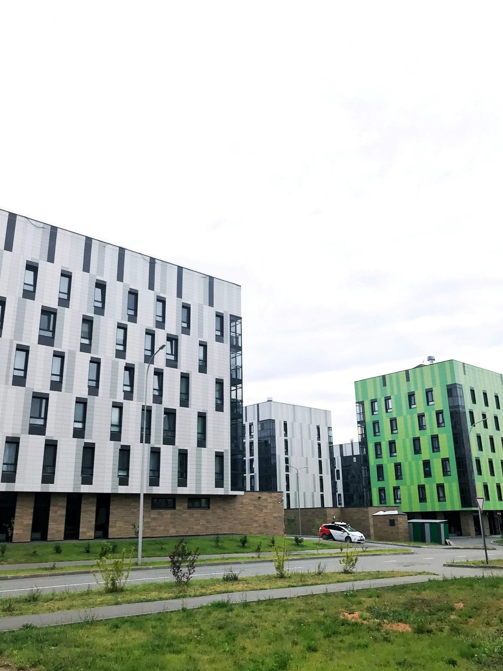 a green and grey building sits among several other buildings