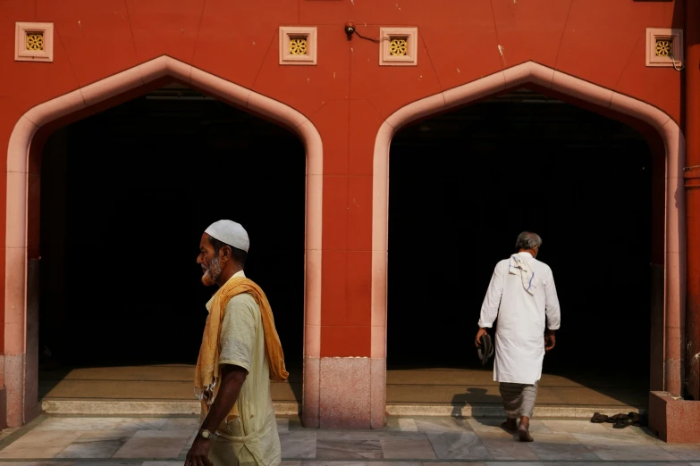 two men walking in front of a large building