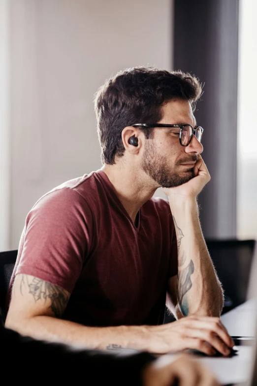 a man with glasses on sitting in front of a computer