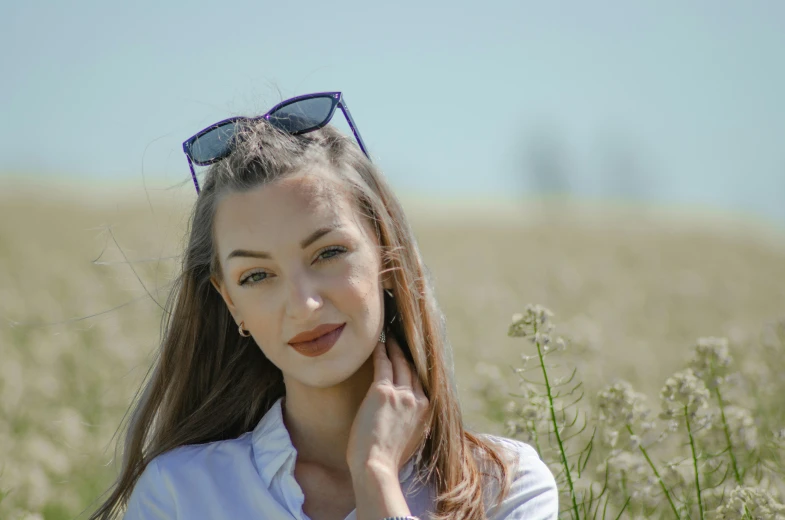 a woman in the middle of a field wearing sunglasses