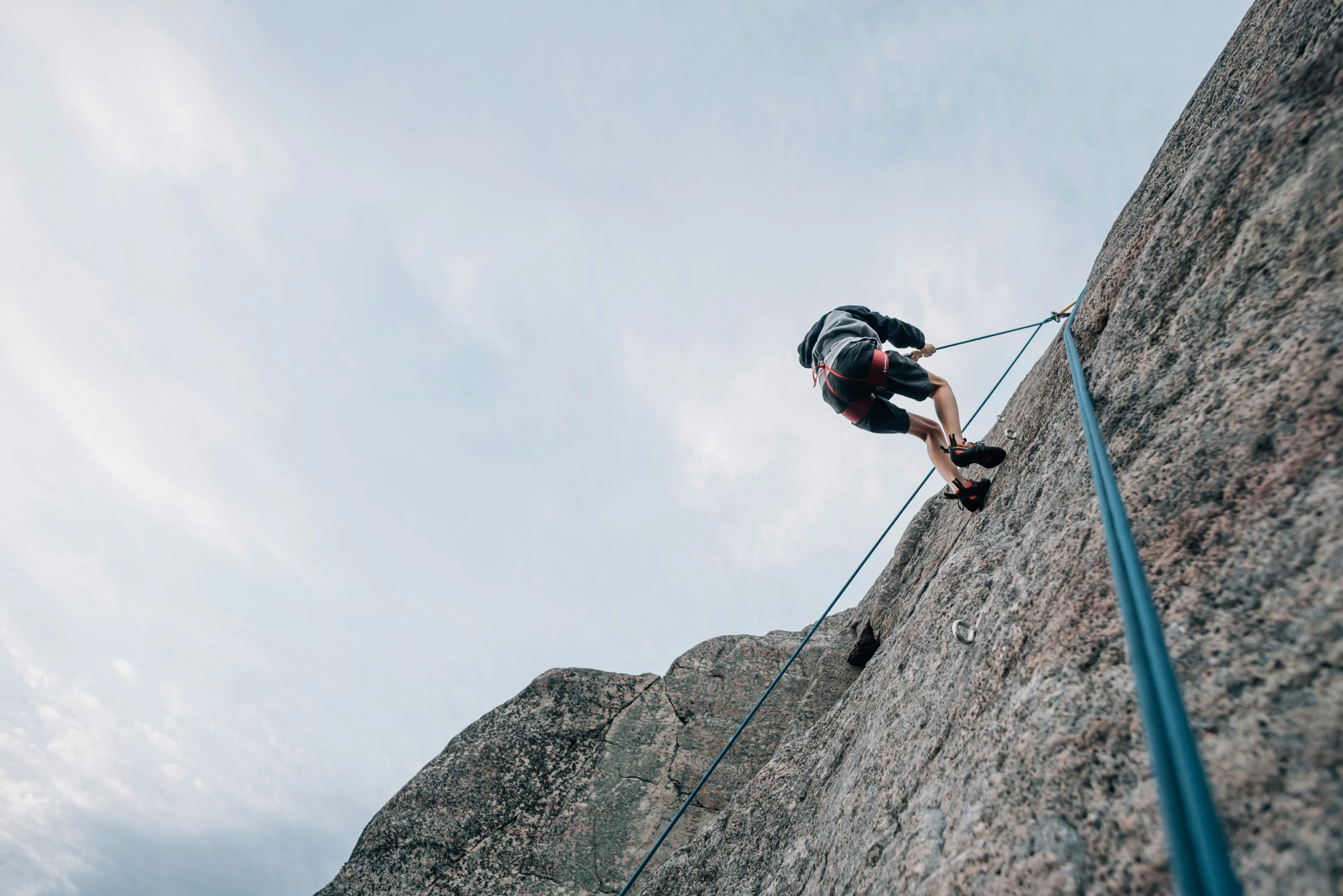 a man in black jacket climbing up a mountain with rope