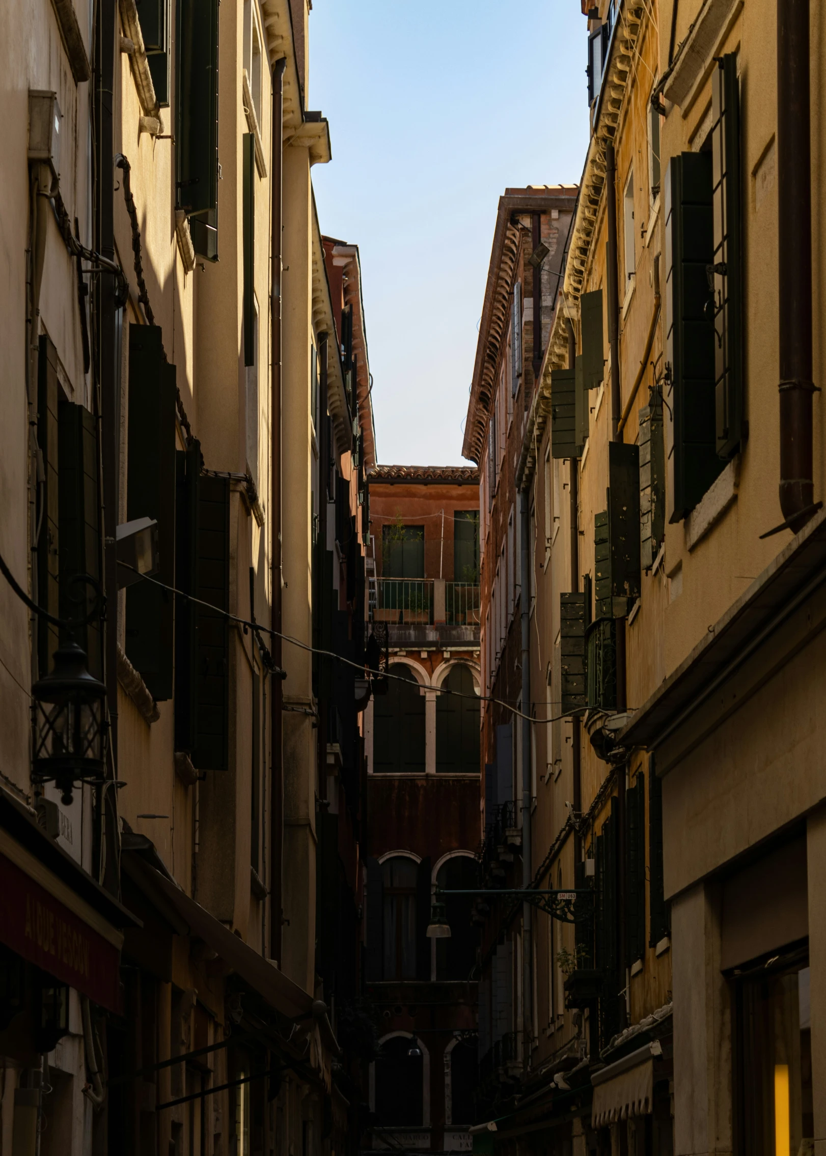 an alley way with buildings and umbrellas on the windows