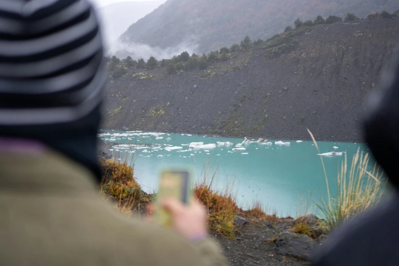 a man holding a camera near a lake