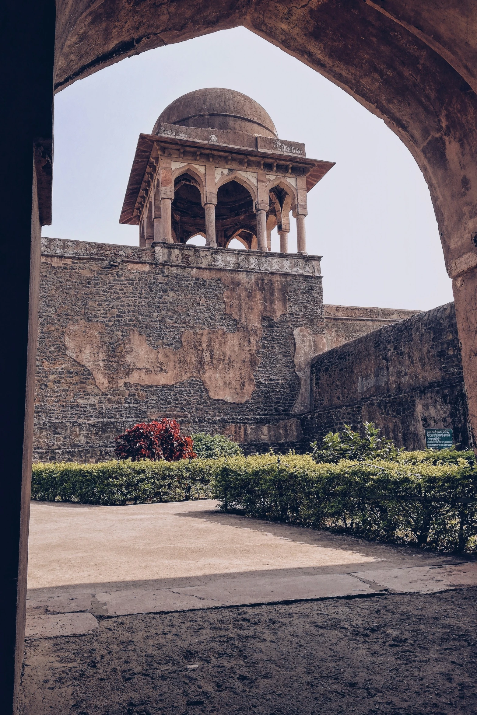 an old building with two arches near some shrubbery